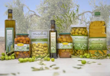 Bodegón con varias botellas de aceite de oliva virgen extra y botes de aceitunas